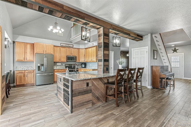 kitchen with light stone countertops, pendant lighting, stainless steel appliances, sink, and a chandelier