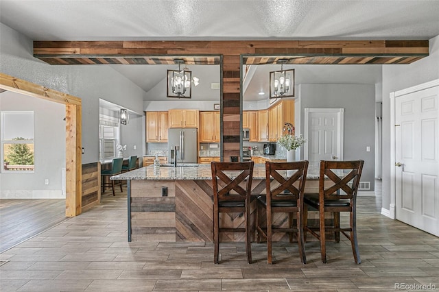 kitchen featuring a kitchen breakfast bar, hanging light fixtures, beam ceiling, light stone countertops, and stainless steel appliances