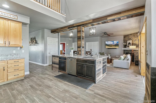 kitchen featuring light brown cabinets, dishwasher, hanging light fixtures, sink, and a fireplace