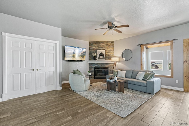 living room featuring ceiling fan, a textured ceiling, and a fireplace