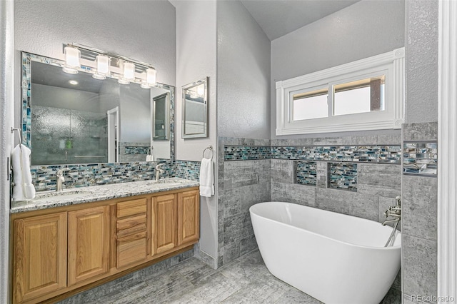 bathroom with tile walls, a bath, and vanity