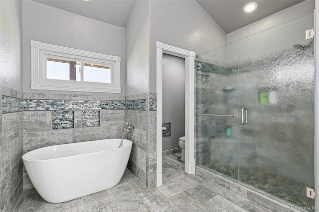 bathroom with separate shower and tub, toilet, and tile walls