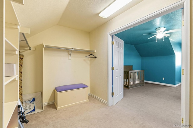 spacious closet featuring ceiling fan, light carpet, and lofted ceiling