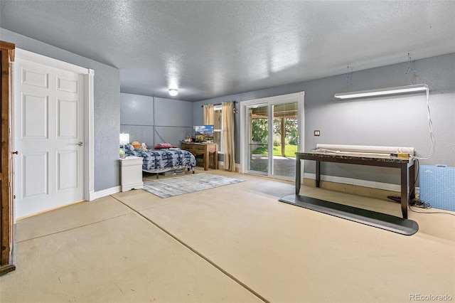 bedroom featuring access to outside, concrete flooring, and a textured ceiling