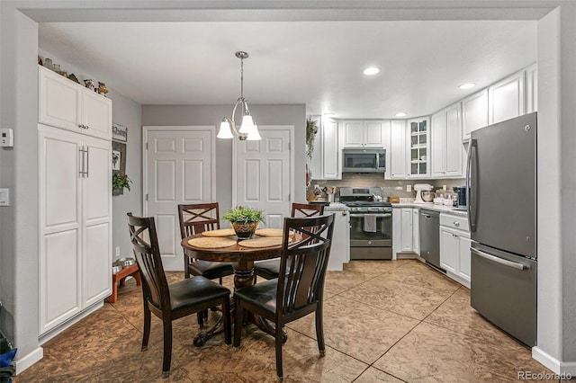 kitchen featuring appliances with stainless steel finishes, tasteful backsplash, light tile patterned floors, white cabinets, and decorative light fixtures