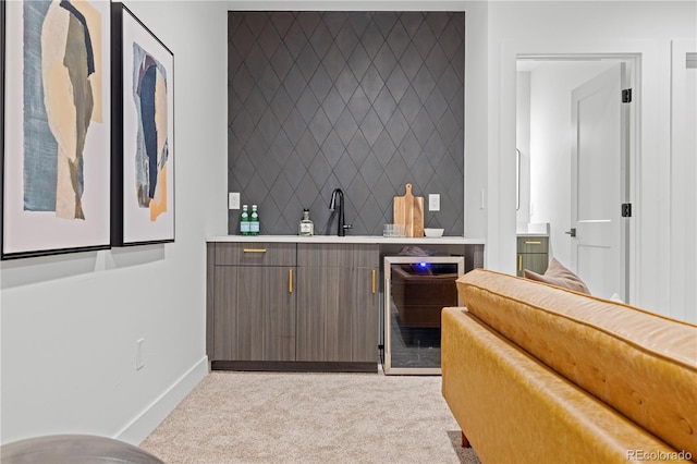 bar featuring sink, dark brown cabinets, light colored carpet, and beverage cooler