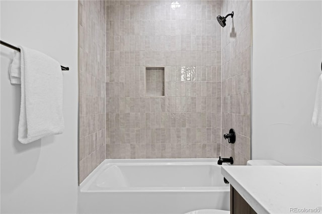 full bathroom featuring tiled shower / bath, vanity, and toilet