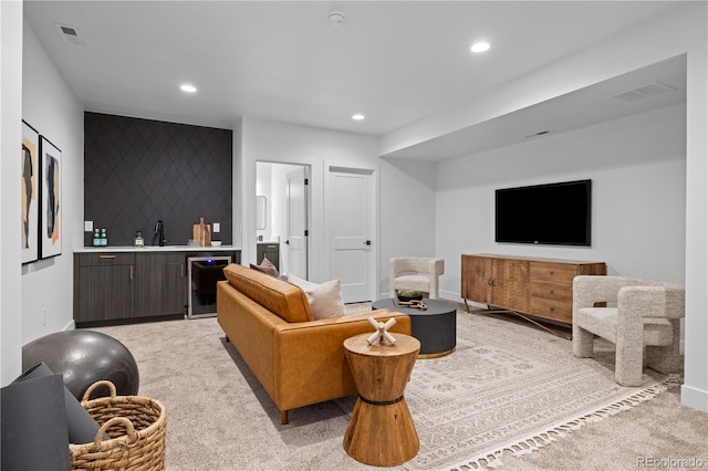 living room with wine cooler, light colored carpet, and wet bar