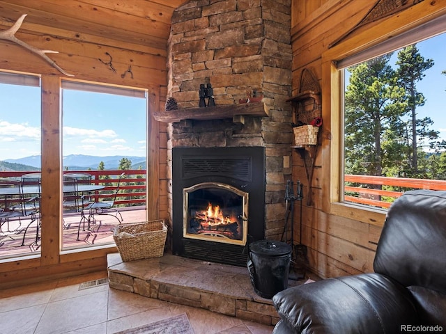 451 Harris Dr, Idaho Springs, CO 80452 - living area featuring tile patterned floors, wooden walls, a mountain view, lofted ceiling, and an outdoor stone fireplace