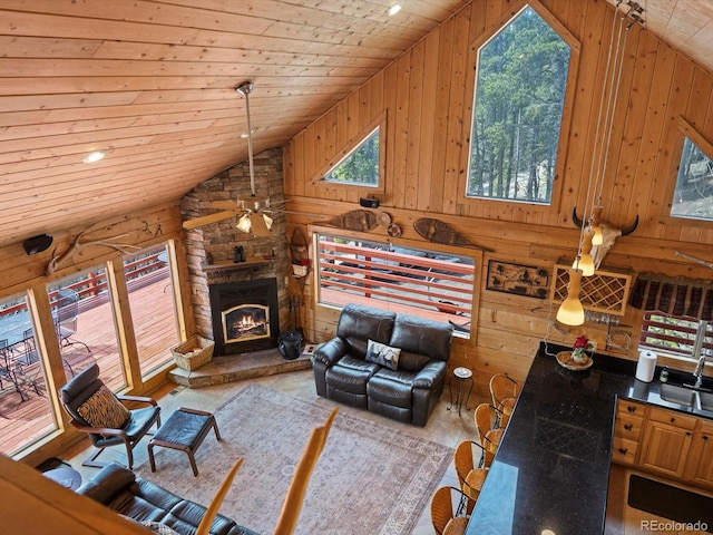 451 Harris Dr, Idaho Springs, CO 80452 - living area with vaulted ceiling, wood ceiling, wood walls, ceiling fan, and a stone fireplace