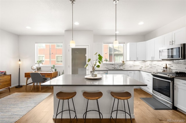 kitchen with a sink, tasteful backsplash, appliances with stainless steel finishes, and a breakfast bar