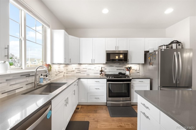 kitchen with decorative backsplash, white cabinets, appliances with stainless steel finishes, and a sink