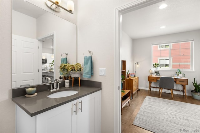 bathroom featuring recessed lighting, baseboards, wood finished floors, and vanity