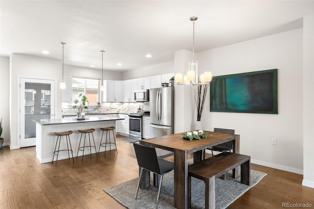 dining space featuring recessed lighting, an inviting chandelier, baseboards, and wood finished floors