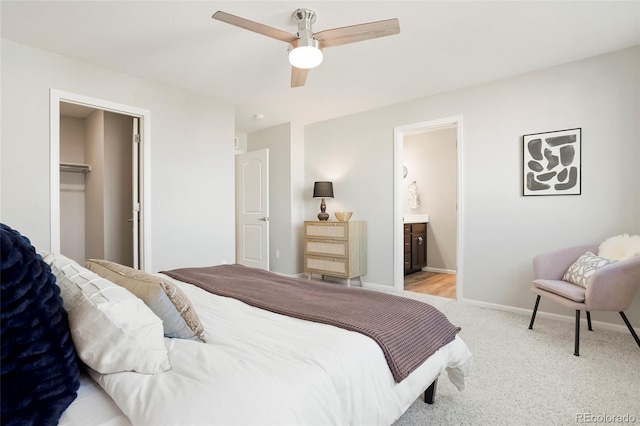 carpeted bedroom featuring connected bathroom, a walk in closet, ceiling fan, and a closet