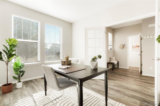 dining room featuring light wood-type flooring and vaulted ceiling