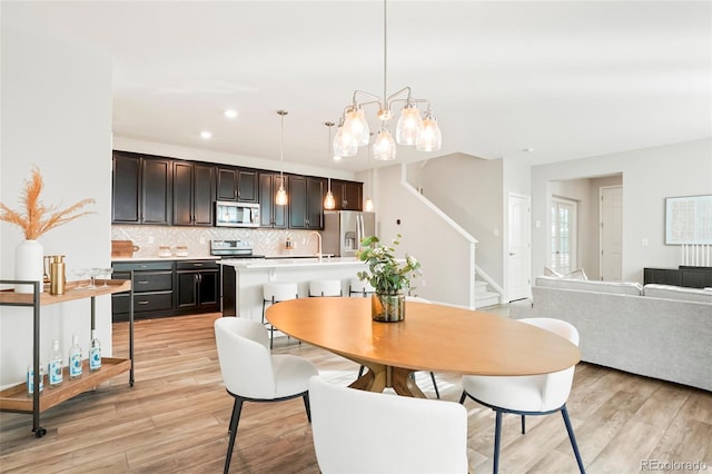 dining room featuring light wood-type flooring, sink, and an inviting chandelier