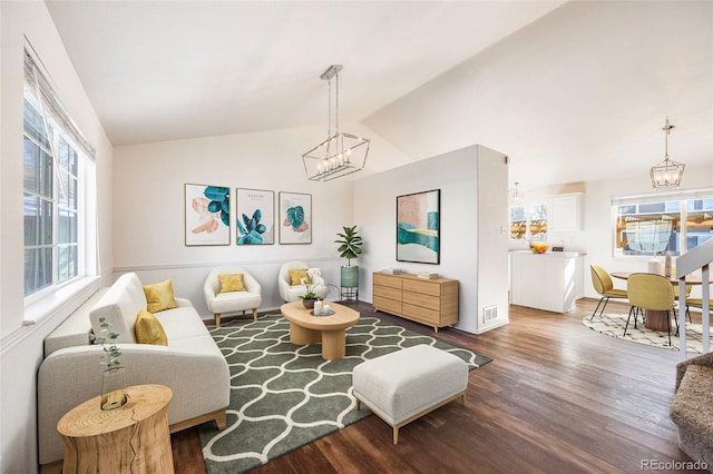 living room with an inviting chandelier, hardwood / wood-style flooring, plenty of natural light, and lofted ceiling