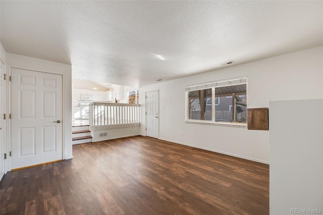 unfurnished room featuring dark wood-type flooring and a textured ceiling