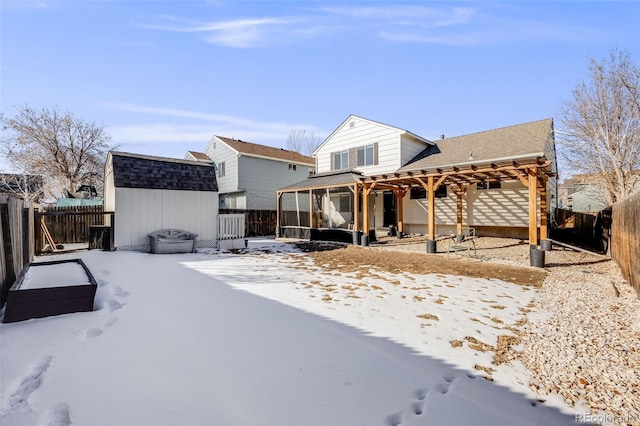 snow covered rear of property featuring a shed and a pergola