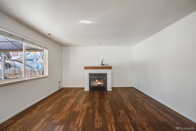 unfurnished living room featuring a textured ceiling and dark hardwood / wood-style flooring