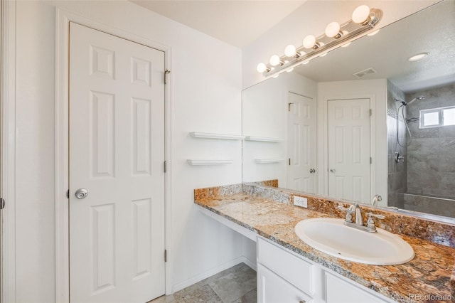 bathroom with a tile shower and vanity