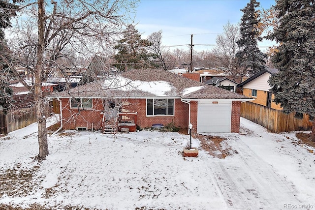 snow covered back of property with a garage