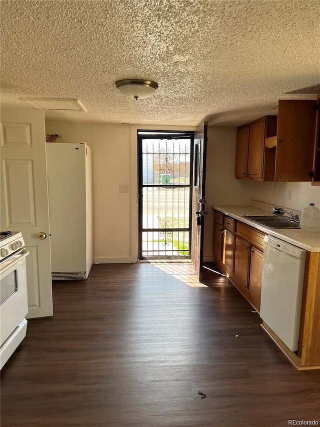 kitchen with a textured ceiling, dark hardwood / wood-style floors, white appliances, and sink