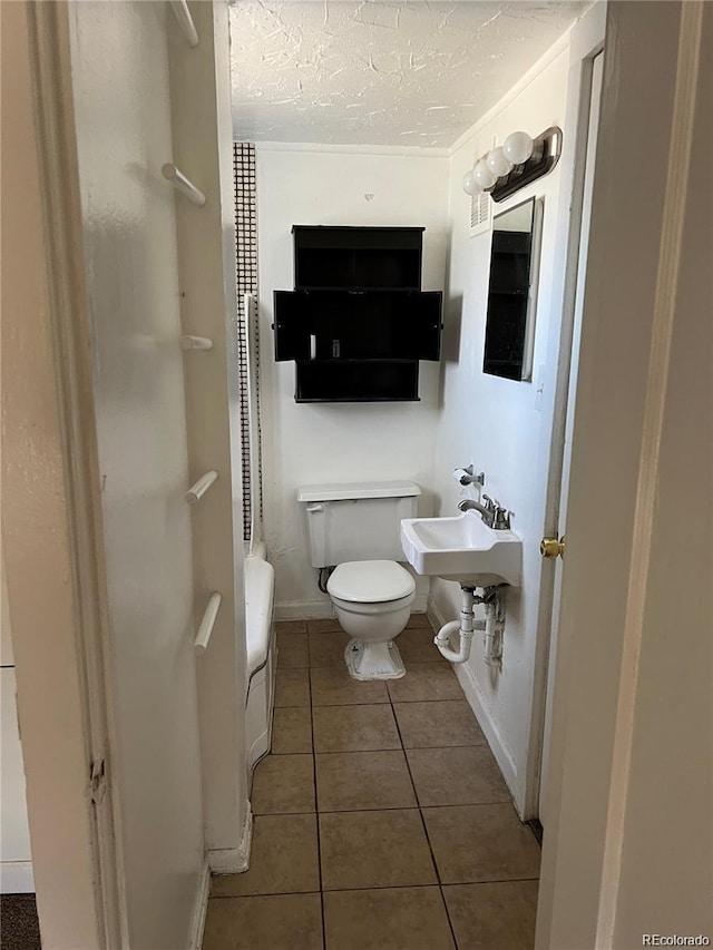 bathroom featuring tile patterned floors, sink, a textured ceiling, and toilet