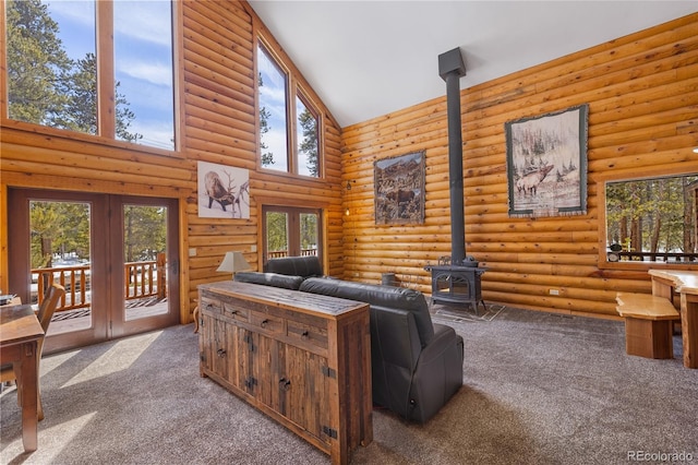 carpeted living area with a wood stove, french doors, a wealth of natural light, log walls, and high vaulted ceiling