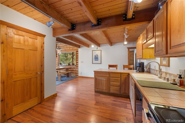 kitchen with a sink, tile countertops, wood ceiling, light wood-style flooring, and rail lighting