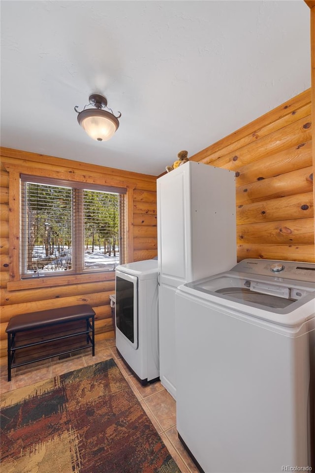 clothes washing area featuring log walls, laundry area, and light tile patterned floors