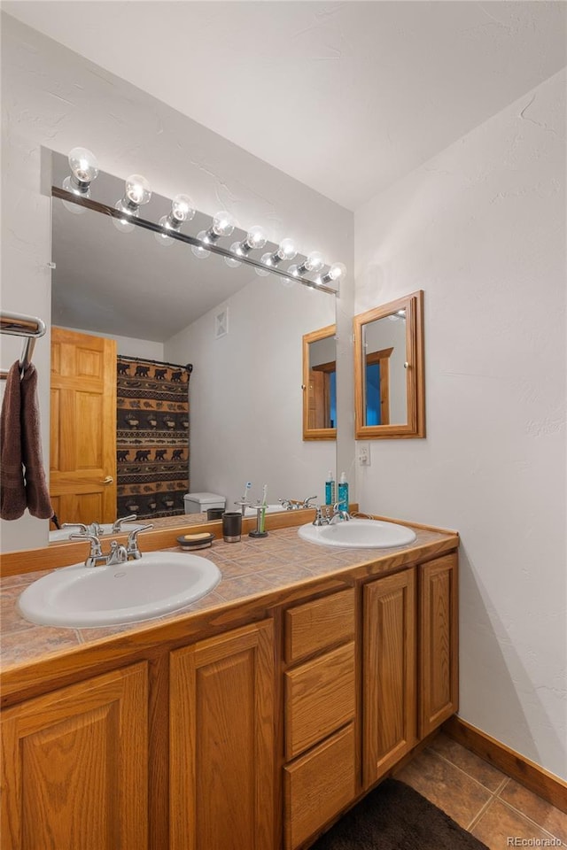 bathroom with tile patterned flooring, a sink, and double vanity