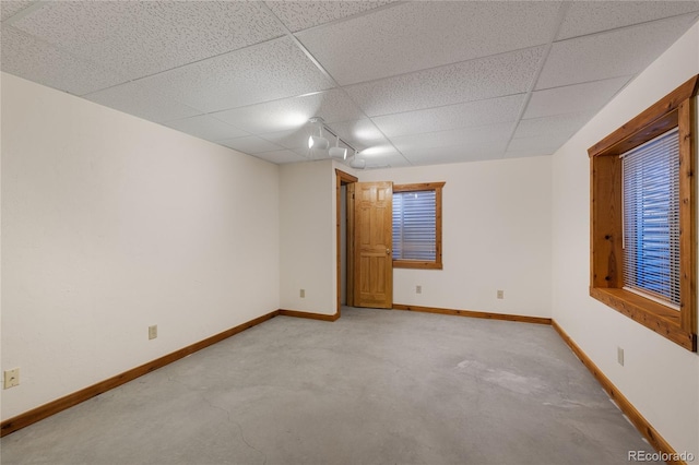 spare room featuring a paneled ceiling, baseboards, and light colored carpet