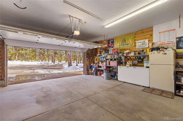 garage featuring a garage door opener, a workshop area, and freestanding refrigerator