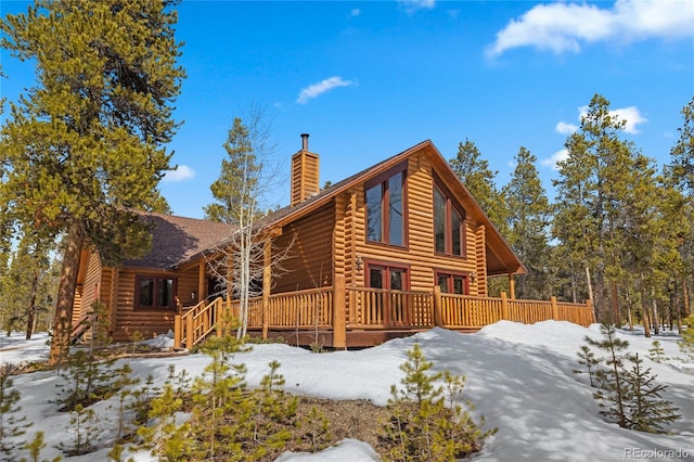 view of front of property featuring a chimney, log exterior, and a deck