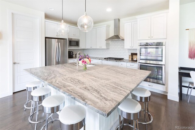 11880 W 38th Pl, Wheat Ridge, CO 80033 - kitchen featuring stainless steel appliances, wall chimney exhaust hood, a sink, dark wood-style floors, and white cabinetry
