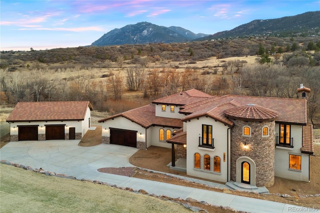 mediterranean / spanish-style house with stucco siding, stone siding, driveway, and a mountain view