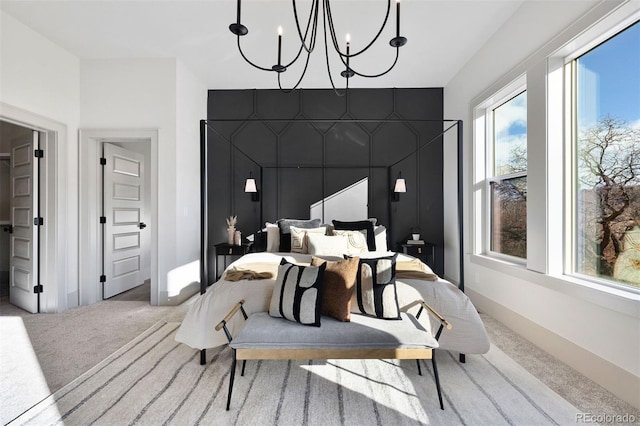 bedroom featuring an accent wall, light colored carpet, baseboards, and a chandelier