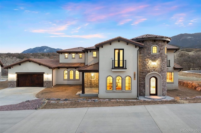 mediterranean / spanish-style house featuring driveway, an attached garage, stucco siding, stone siding, and a tile roof