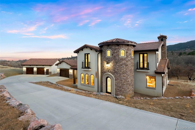 mediterranean / spanish-style home featuring stucco siding, a tiled roof, a chimney, and a balcony