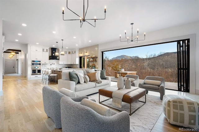 living area with a chandelier, light wood finished floors, and arched walkways