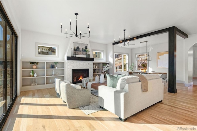 living area with a glass covered fireplace, wood finished floors, arched walkways, and a chandelier