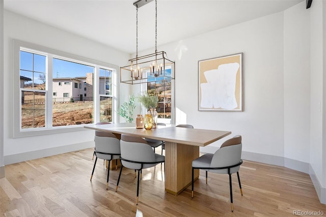 dining space featuring light wood-type flooring, baseboards, and a chandelier