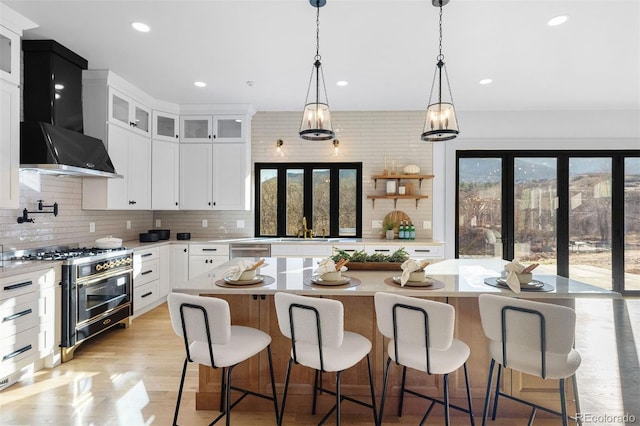 kitchen featuring backsplash, appliances with stainless steel finishes, light countertops, and wall chimney range hood