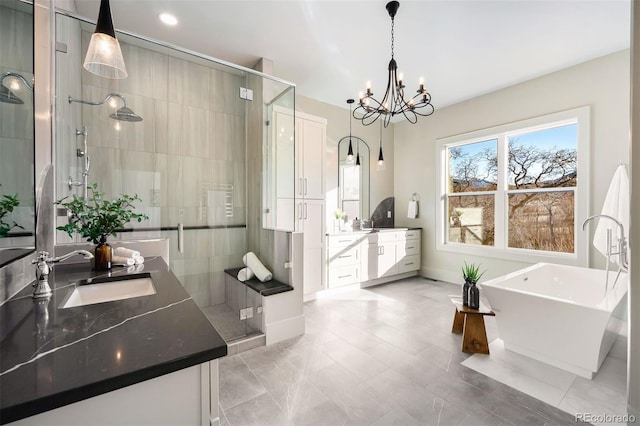 full bath with a notable chandelier, a shower stall, vanity, and a freestanding tub