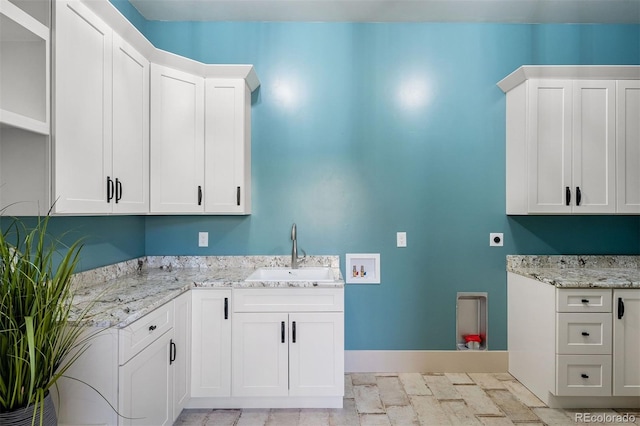 clothes washing area with baseboards, hookup for a washing machine, cabinet space, electric dryer hookup, and a sink