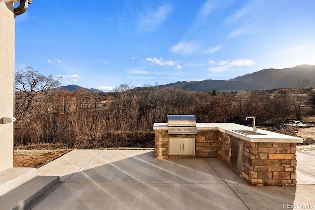 view of patio with grilling area, an outdoor kitchen, and a mountain view