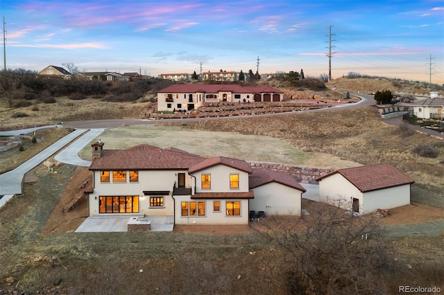 back of property at dusk featuring stucco siding