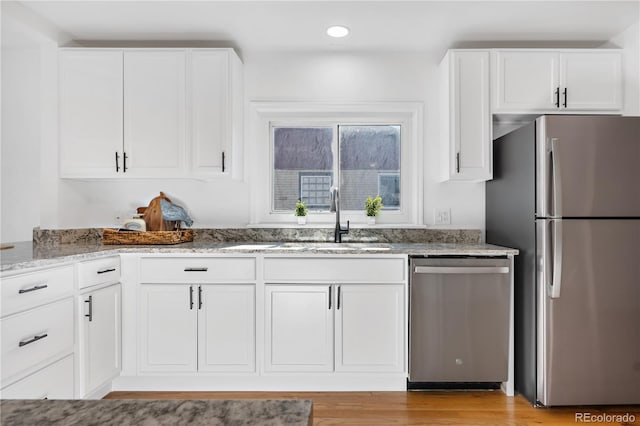 kitchen featuring light hardwood / wood-style floors, sink, light stone countertops, stainless steel appliances, and white cabinets